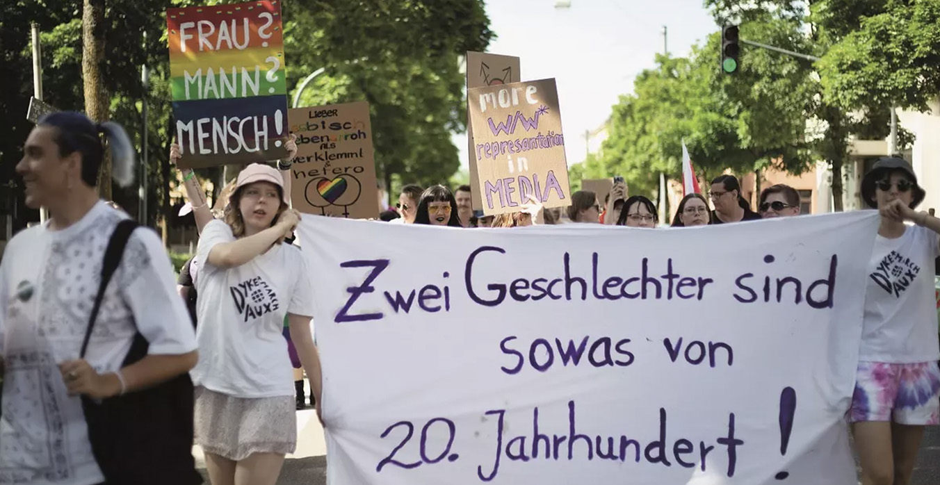 Das Bild zeigt einen Demonstrationsumzug mit einem grossen weissen Transparent, auf dem steht: Zwei Geschlechter sind sowas von 20. Jahrhundert.